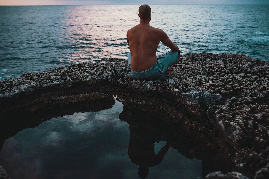 Timo Niessner von hinten sitzt am Was er und übt sich in Gelassenheit