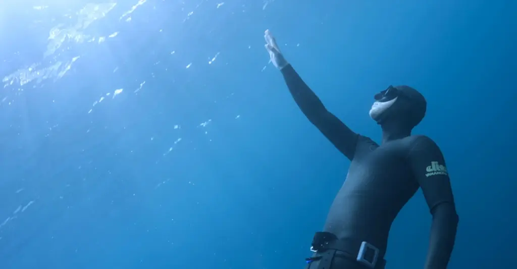 Tim Niessner taucht und streckt Hand Richtung Wasseroberfläche